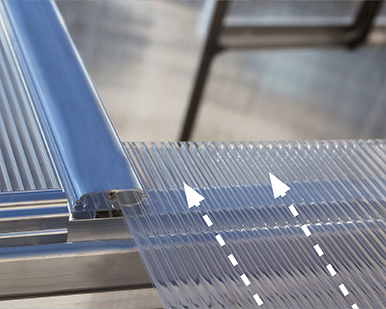 Close-up of a transparent plastic sheet with metal brackets on a reflective surface.