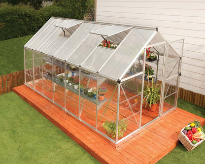 Greenhouse with plants on a wooden deck in a garden setting