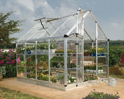 Clear glass greenhouse with plants inside, set against a natural outdoor background.